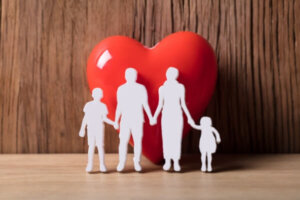 Close-up of a family holding hands besides red heart shape